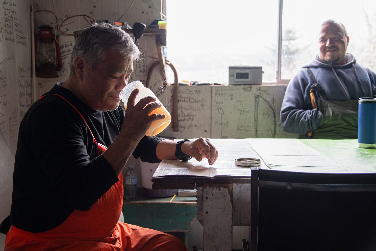 Fisherman Lonny Stewart inhales the scent of a jar of eulachon “grease” at Walter’s Camp, one of the Nisg̱a’a nation’s fishing camps along the Nass River, as Ian Morven looks on.